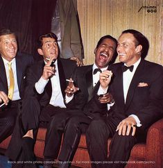 three men in tuxedos sitting on a couch laughing and holding drinks with their mouths open
