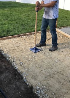 a man is holding a shovel and standing on the ground with gravel in front of him