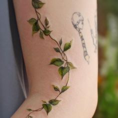 a woman's arm with green leaves on it