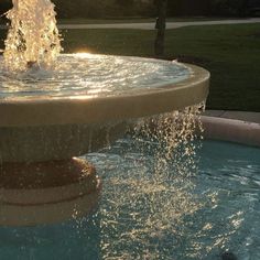 a fountain with water spouting from it's sides in the evening sun