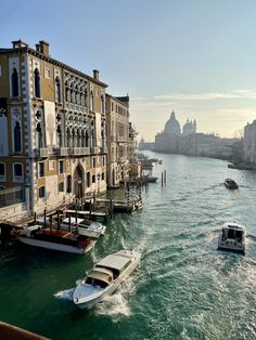 two boats are traveling down the water in front of buildings on both sides of the river