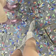 the legs and ankles of two people standing on a floor covered in confetti