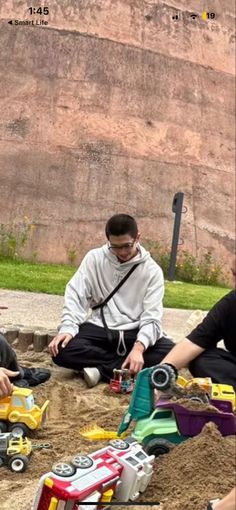 three people sitting on the ground playing with toys