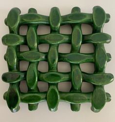 a close up of a green tile design on a white wall in the shape of an interwoven structure