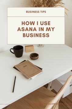 a white table with a book, coffee cup and pen on it that says how i use asana in my business