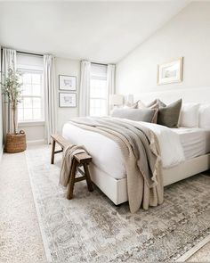 a bedroom with a large bed and rugs on the floor in front of two windows