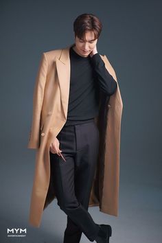 a man in a trench coat and black pants is posing for a magazine cover photo