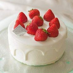 a white cake topped with lots of strawberries on top of frosted icing