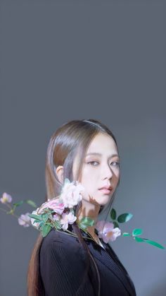 a woman with long hair and flowers in her hair is looking at the camera while wearing a black top