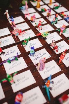 the table is covered with lots of different colored paper birds and place cards for each individual