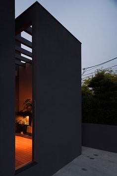 an open door on the side of a building at night with trees in the background