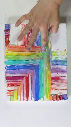 someone is painting on a piece of paper with different colors and shapes in the background