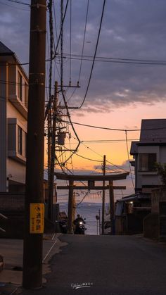 an empty street next to the ocean with power lines in the air and buildings on both sides