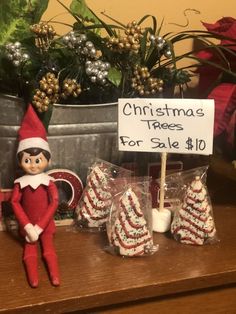 an elf is sitting next to some candy canes and a sign that says christmas trees for sale 10