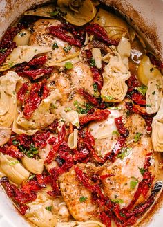 a pot filled with pasta and chicken covered in red sauce, garnished with parsley