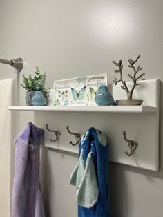 two towels are hanging on the wall next to hooks and towel holders with plants in them