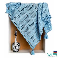 a blue crocheted blanket sitting on top of a wooden shelf next to a zebra figurine