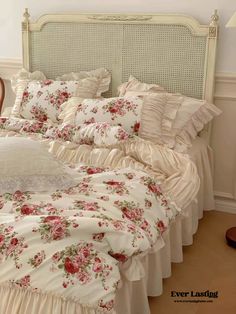 a white bed with pink flowers and ruffles on the comforter is shown