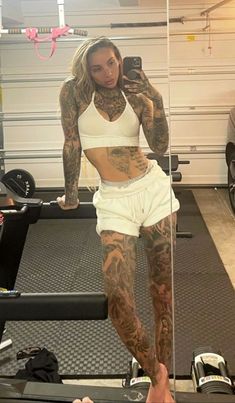 a woman with tattooed arms and legs standing on a treadmill