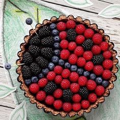 a pie with berries, raspberries and blueberries in it on a wooden table