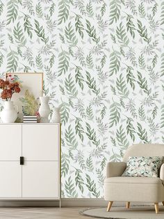 a living room with a white chair and green leaves wallpaper on the wall behind it