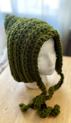 a crocheted green hat on top of a white mannequin head