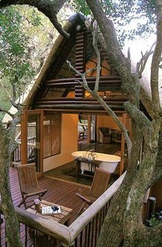 an outside view of a wooden cabin with a bathtub in the treehouse area