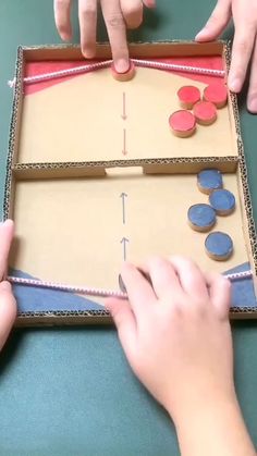 two hands are placing buttons in a cardboard box