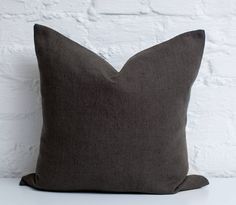 a gray pillow sitting on top of a white table