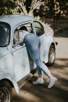 a woman leaning on the side of a car with her head in the door window