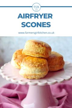 three scones sitting on top of a white cake plate with pink cloth around it