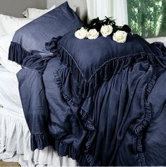 three white roses are placed on top of a blue comforter in a bed room