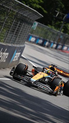 a race car driving down the road with another car behind it in front of him