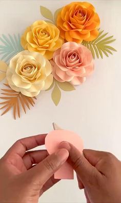 someone is cutting out paper flowers on a white surface with scissors and glue to them