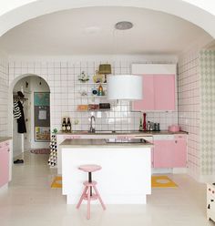 a pink and white kitchen with stools in it