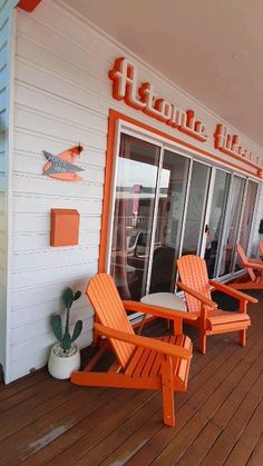 two orange chairs sitting on top of a wooden deck