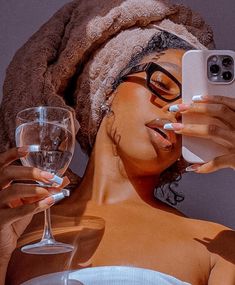 a woman with glasses and a towel on her head taking a selfie while holding a wine glass