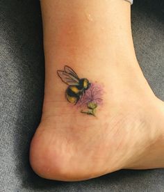 a small tattoo on the foot of a woman with a bee sitting on top of a flower