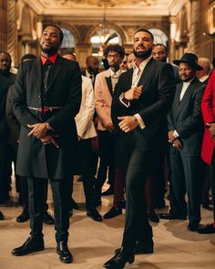 two men in tuxedos are standing next to each other with others looking on