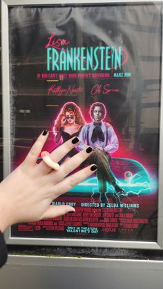 a person's hand with black nail polish holding up a poster for the film