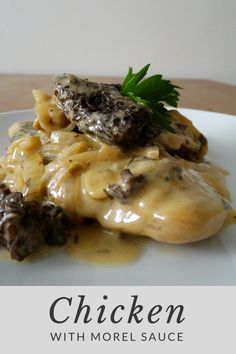 a white plate topped with pasta and meat covered in sauce on top of a wooden table