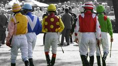 three jockeys are walking down the street in front of a crowd wearing colorful outfits