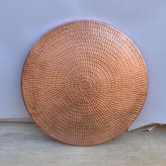 a brown plate sitting on top of a wooden table next to a white wall and floor