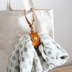 a white bag with polka dots and a brown leather keychain hanging from it