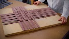 a person is working on some kind of art project with wood strips and glues