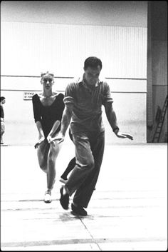 black and white photograph of three people playing with a frisbee in an indoor gym