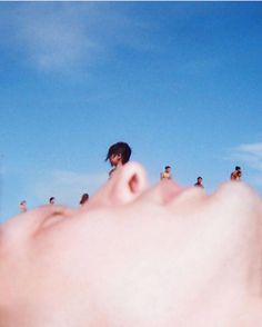 a person laying down on the beach with their head in the air and people behind them