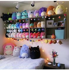 there are many stuffed animals on the shelves above the bed and in the room behind them