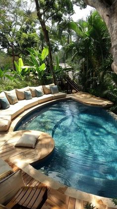 an outdoor swimming pool with lounge chairs around it, surrounded by trees and greenery