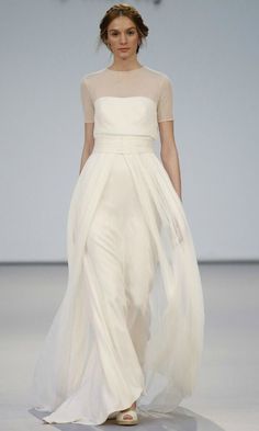 a woman walking down a runway wearing a white dress